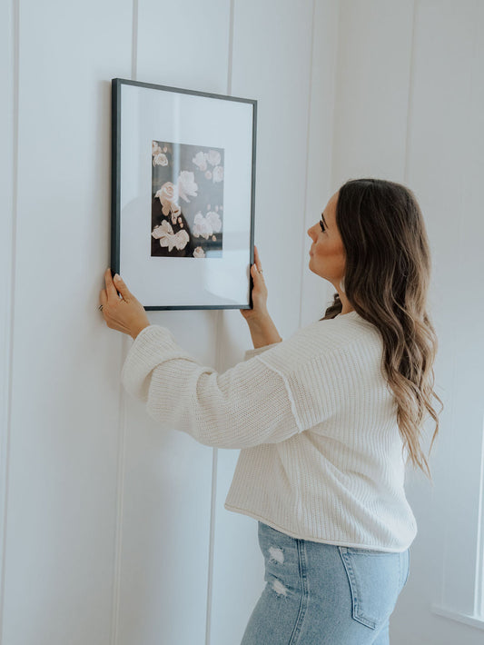 Ayara founder Lori Frost hanging a framed art print on the wall.