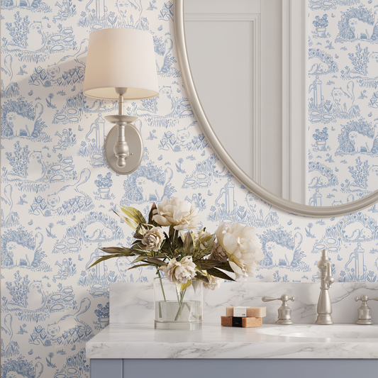 Bathroom with decorative Cat Toile wallpaper, round mirror, and floral arrangement.