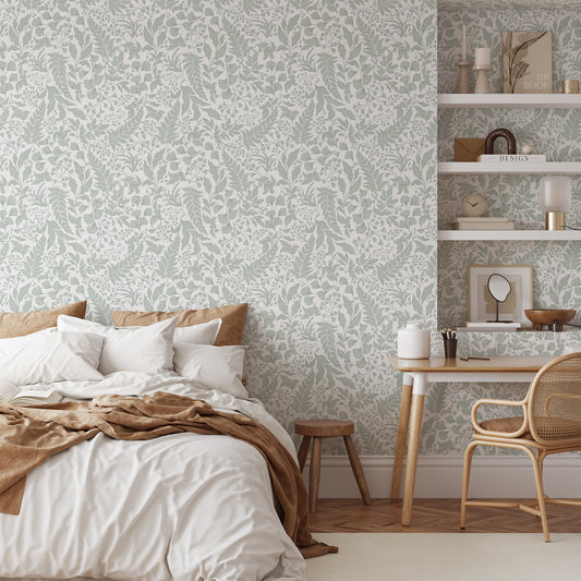 Neatly made bed with white bedding and brown blanket in a room with patterned wallpaper and a small desk.