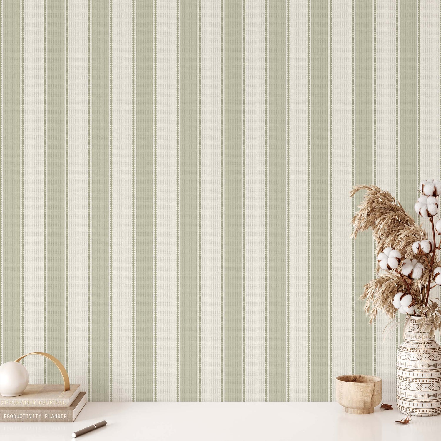 Striped wallpaper with a vase of cotton and decorative items on a table