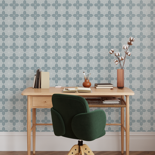 Wooden desk with green chair against a wallpapered wall.