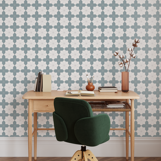 Wooden desk with green chair against a patterned wallpapered wall.