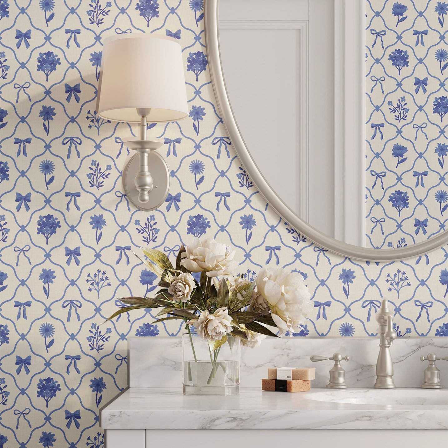 Bathroom with our Something Blue wallpaper with blue ribbons and flowers, a round mirror, and marble countertop.