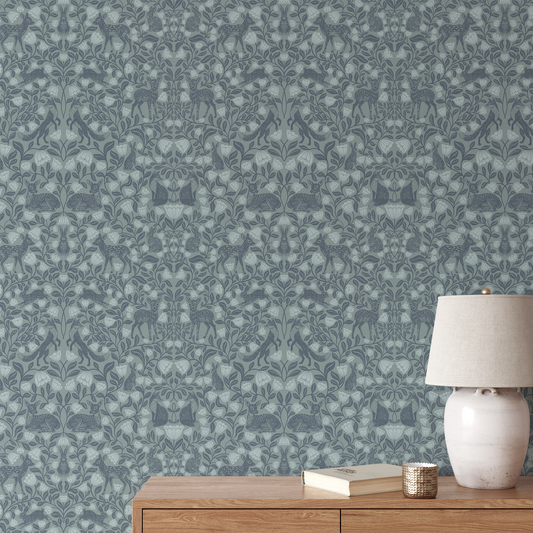 Patterned wallpaper with a deer and floral design in blue tones, featuring a wooden side table with a lamp and books.