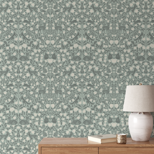 Wallpaper with a nature-themed pattern featuring animals and plants, with a wooden side table and lamp in the foreground.